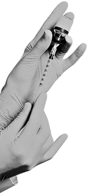 Gloved hands filling needle with serum